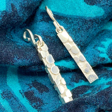 Load image into Gallery viewer, Earring dangles with organic raised round texture, displayed on green patterned cloth
