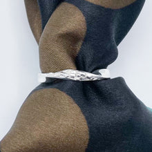 Load image into Gallery viewer, Textured twist ring threaded on a roll of cloth, top down view of the twist.
