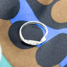 Load image into Gallery viewer, Top down view of the textured twist ring on a colorful cloth surface.
